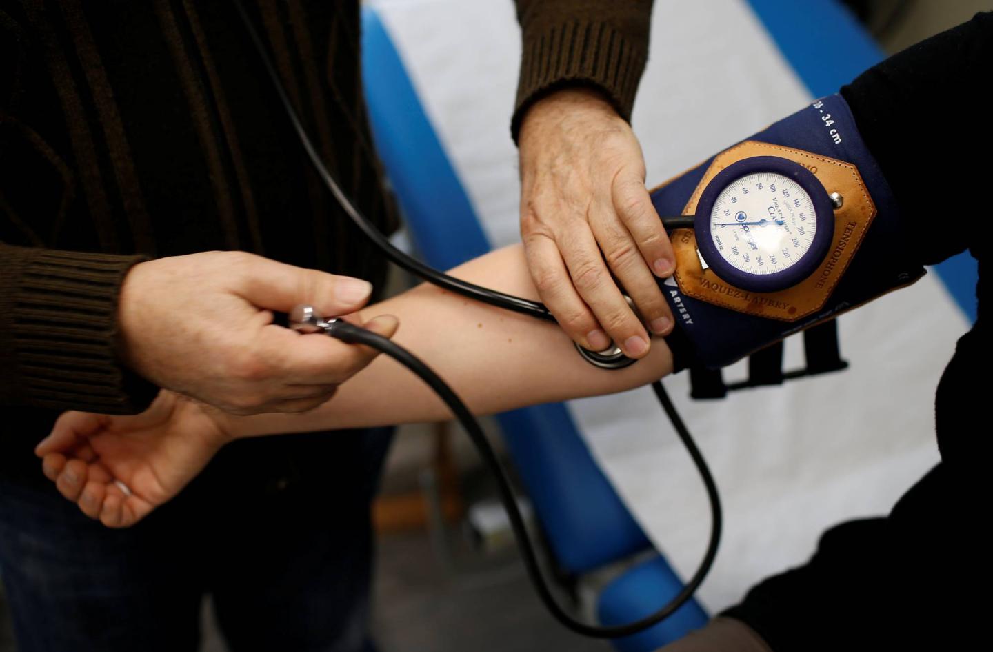 Retired French doctor Jean-Francois Rechner, 67, measures the blood pressure of a patient during a consultation at the 'Service Medical de Proximite' clinic in Laval