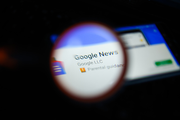 Google News app is seen trough a magnifying glass on an