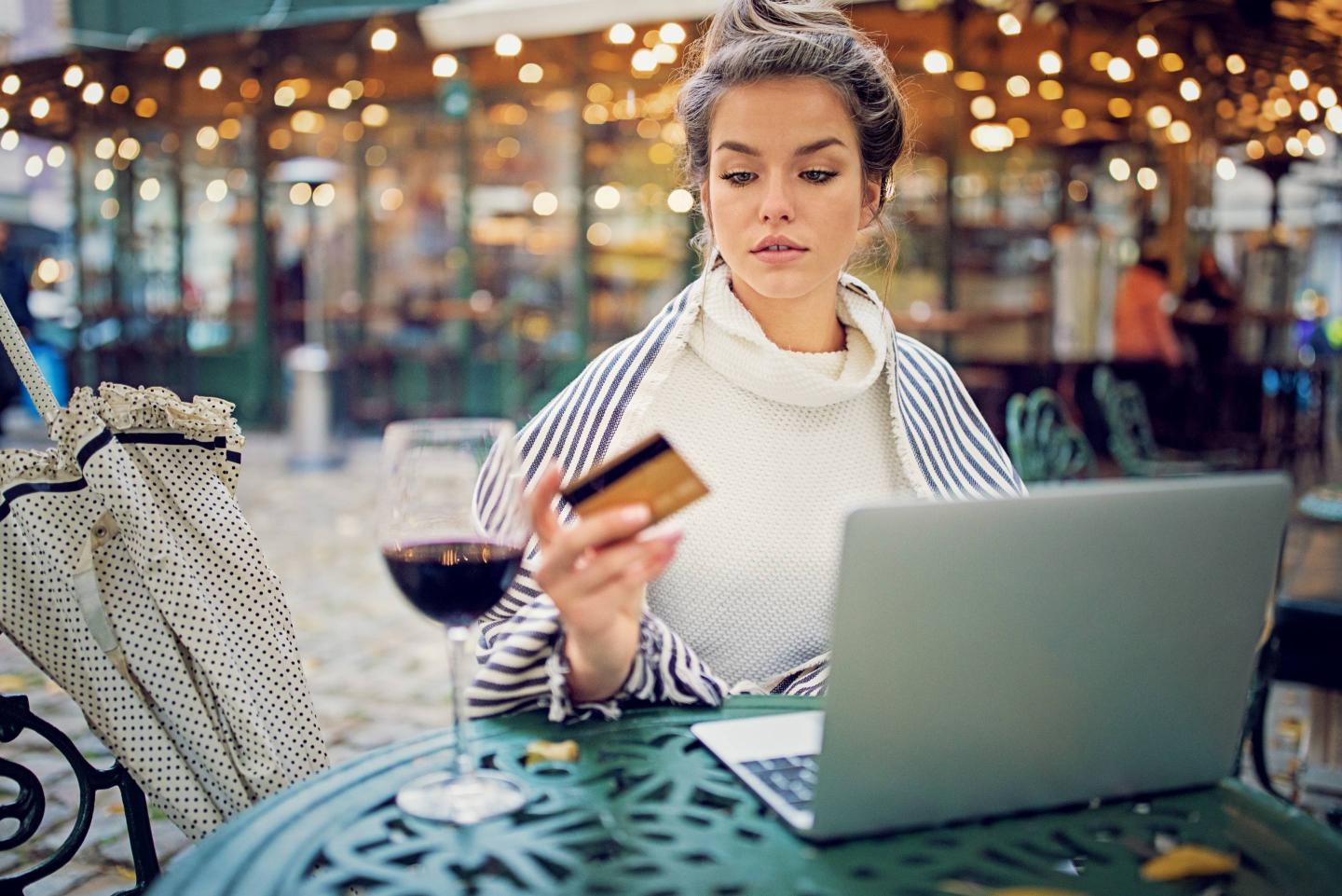 Young woman is shopping online using her credit card and laptop in a rainy day