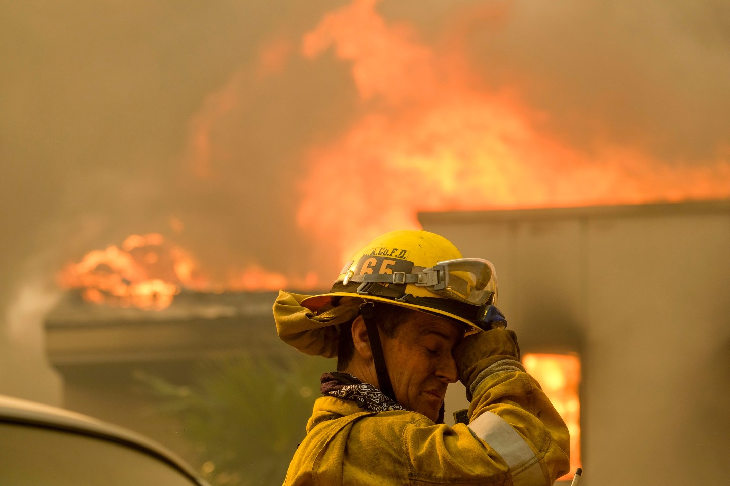 A firefighter keeps watch as the wildfire burns a home near Malibu Lake in Malibu, Calif.