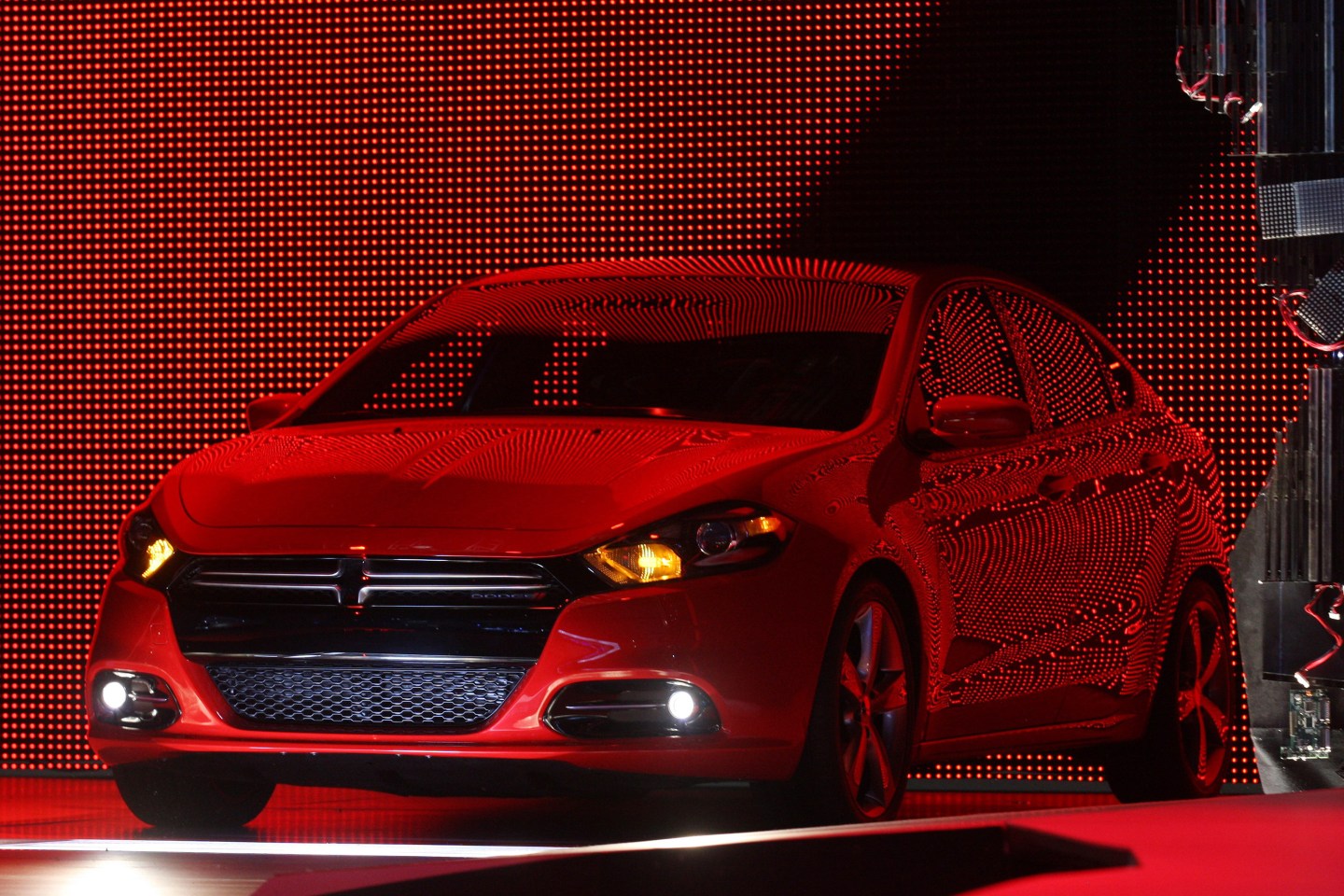 The 2013 Dodge Dart reflects lights as it is unveiled during the first press preview day for the North American International Auto Show in Detroit