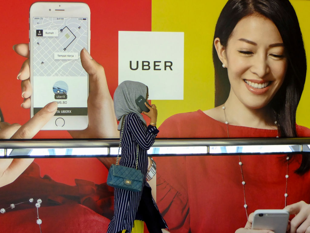 A women is seen passing by an Uber advertisement at Kuala