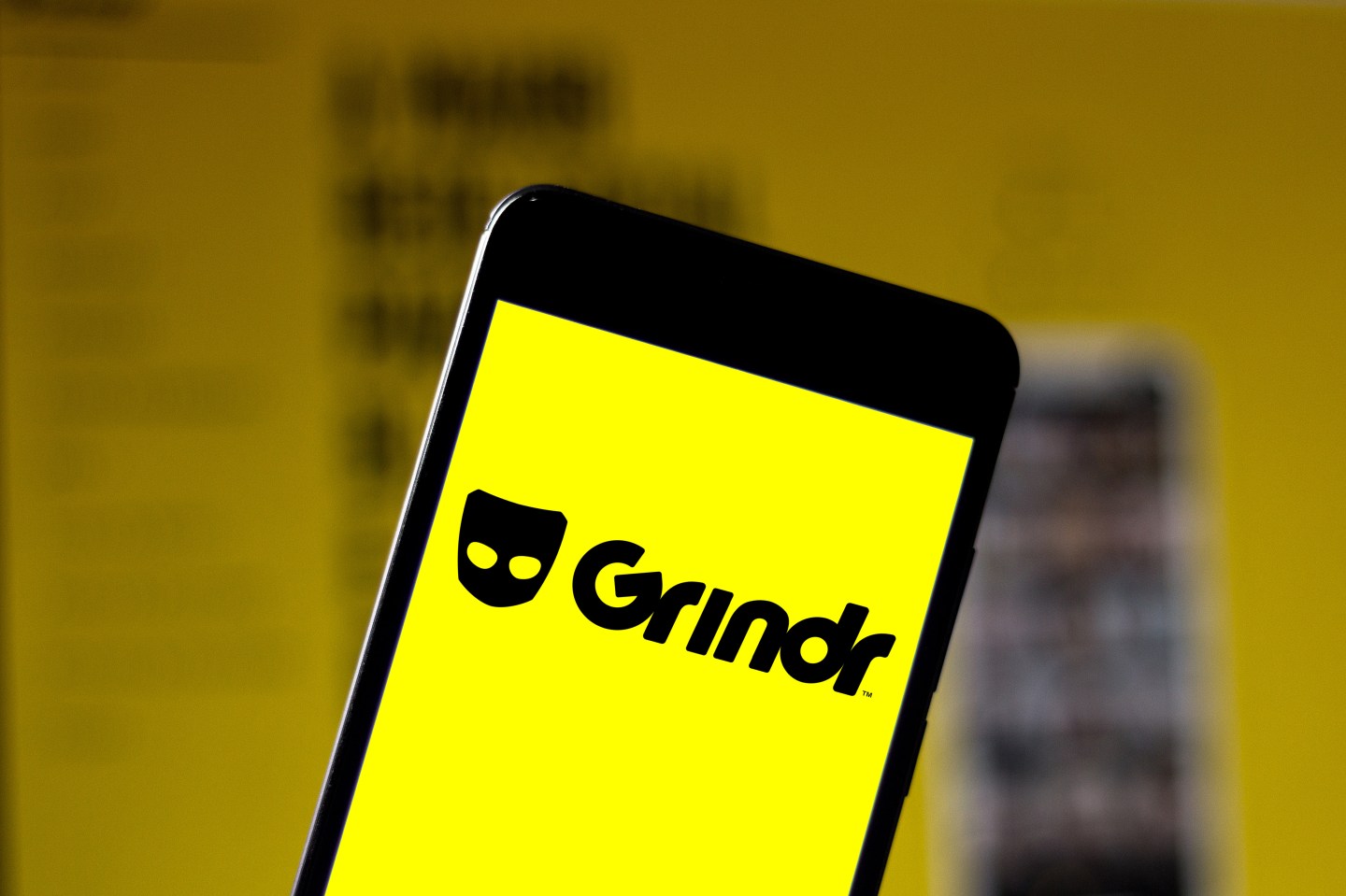 In this photo illustration a Grindr logo seen displayed on a