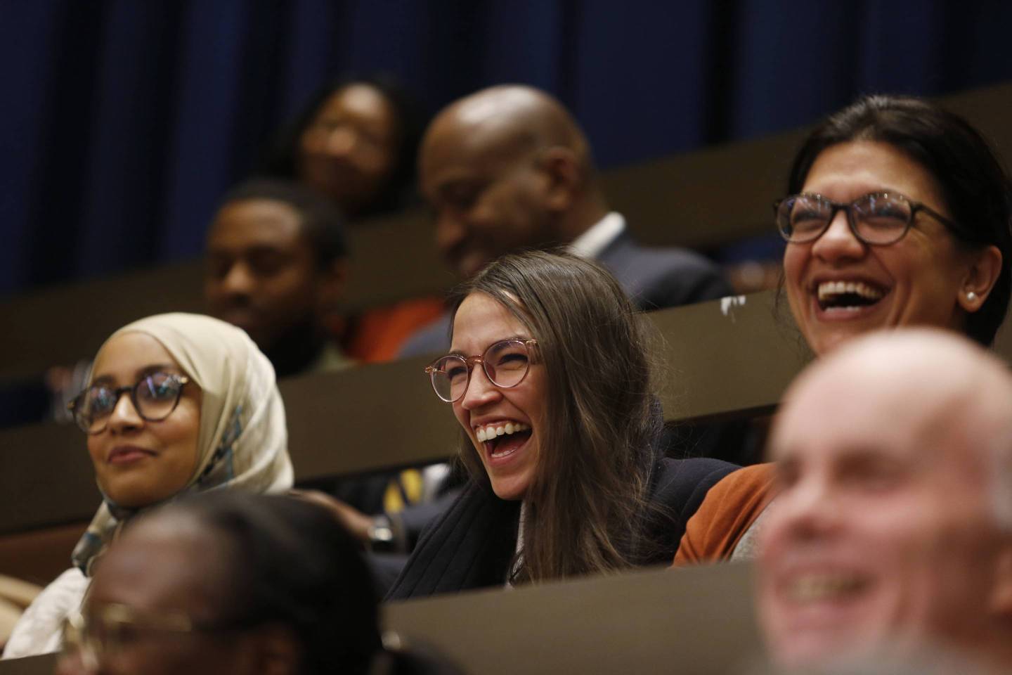 Alexandria Ocasio-Cortez and Rashida Tlaib laugh at a Boston City Council meeting on Dec. 5, 2018.