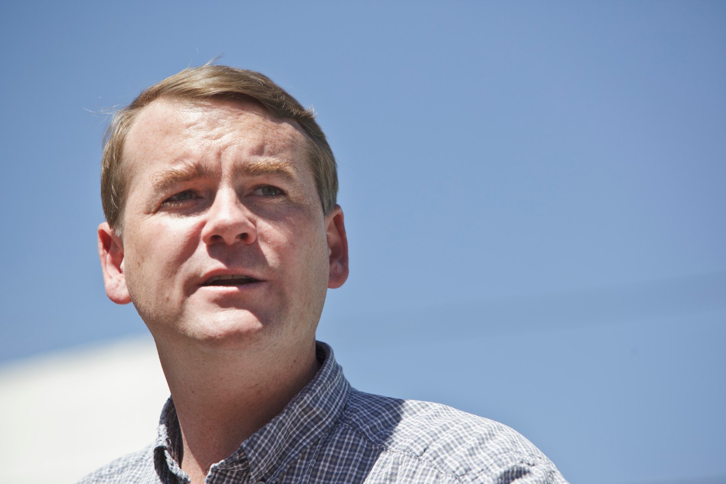 Sen. Michael Bennet stands against a sky backdrop.
