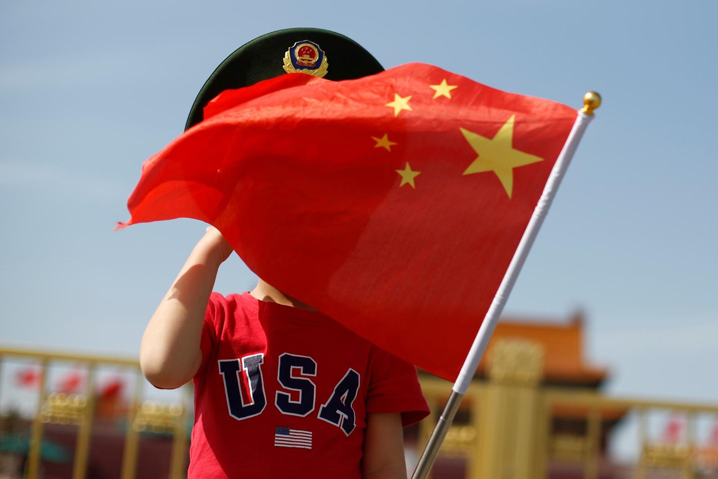 A boy wearing an U.S. t-shirt waves a Chinese national flag in Tiananmen Square in Beijing