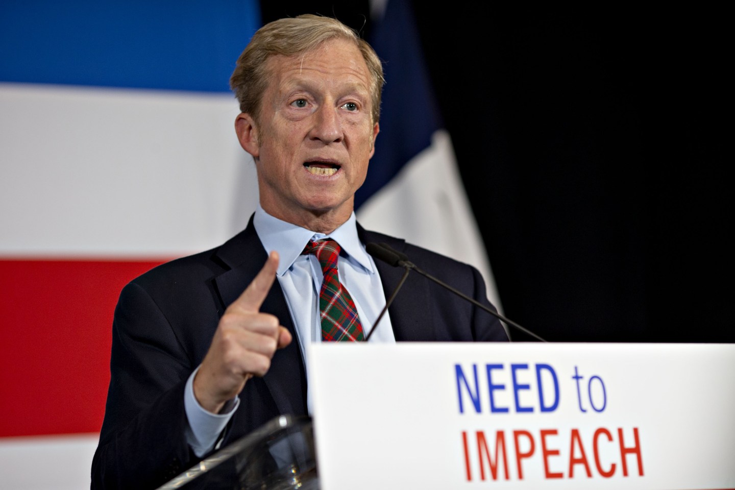 Tom Steyer speaking at a podium that reads "Need to Impeach"