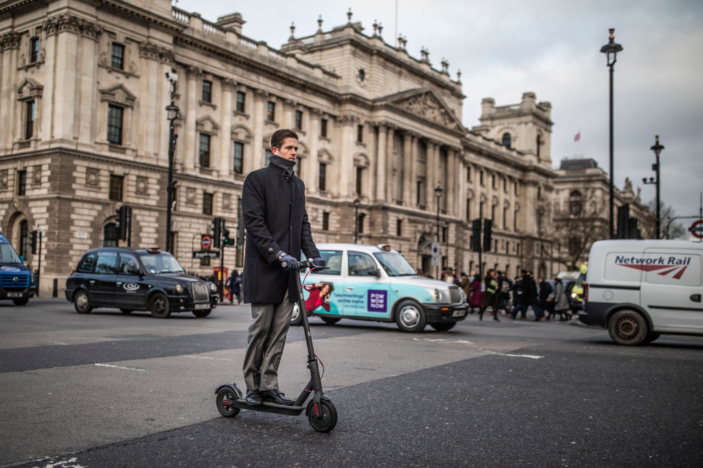A man rides an e-scooter past Parliament Square in London, England earlier this year.