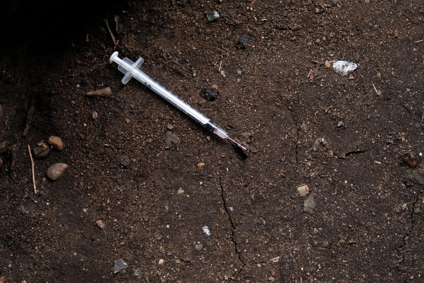 A used syringe in the dirt.