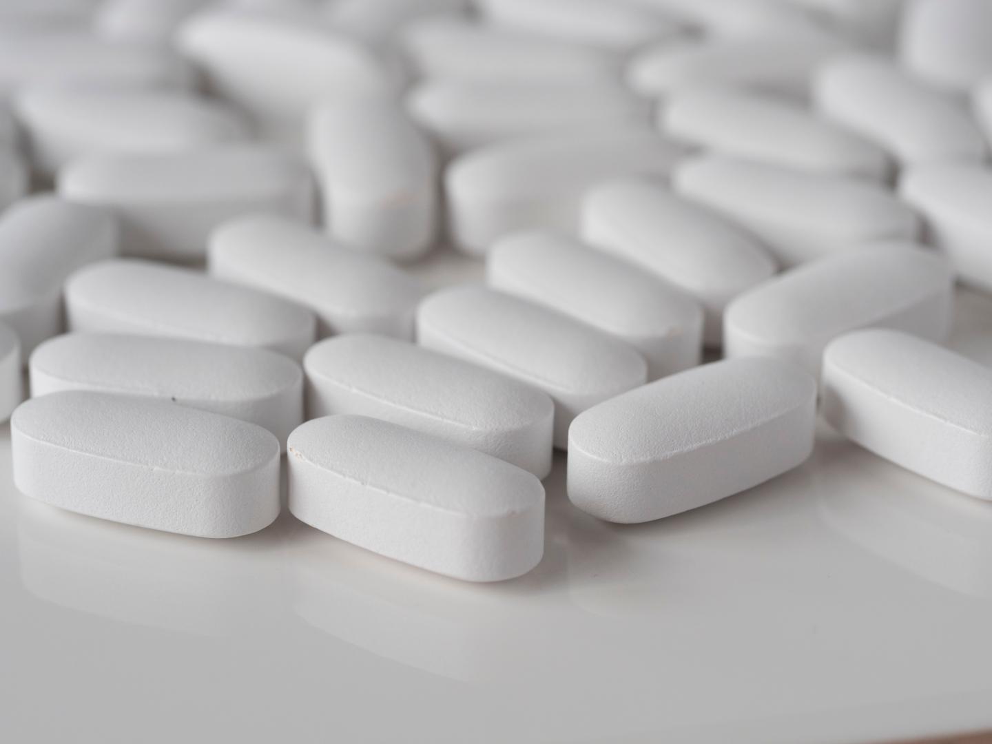 White pills lay on a white surface