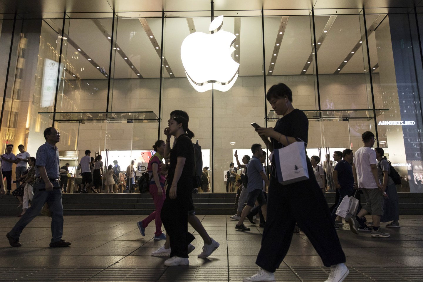 Pedestrians walk past an Apple Inc. store in Shanghai, China, on Monday, July 29, 2019. Chinese trade negotiators will host their U.S. counterparts at a landmark of jazz-era Shanghai on the city's riverside Bund, re-opening trade talks with a marked change of atmosphere after an almost three-month hiatus. Photographer: