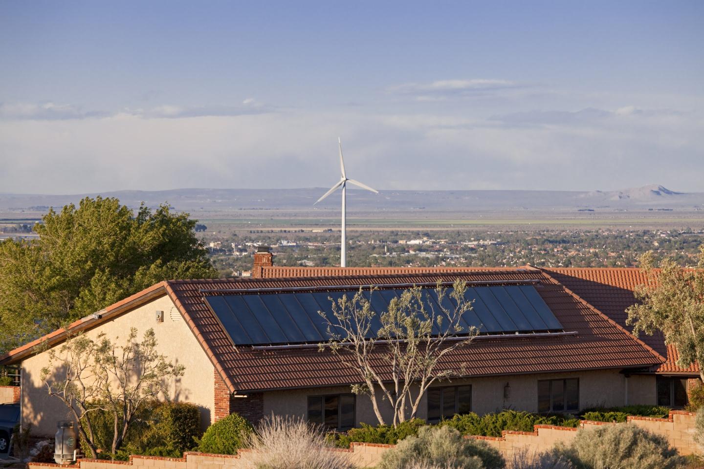 Home with both solar panels and a nearby wind turbine