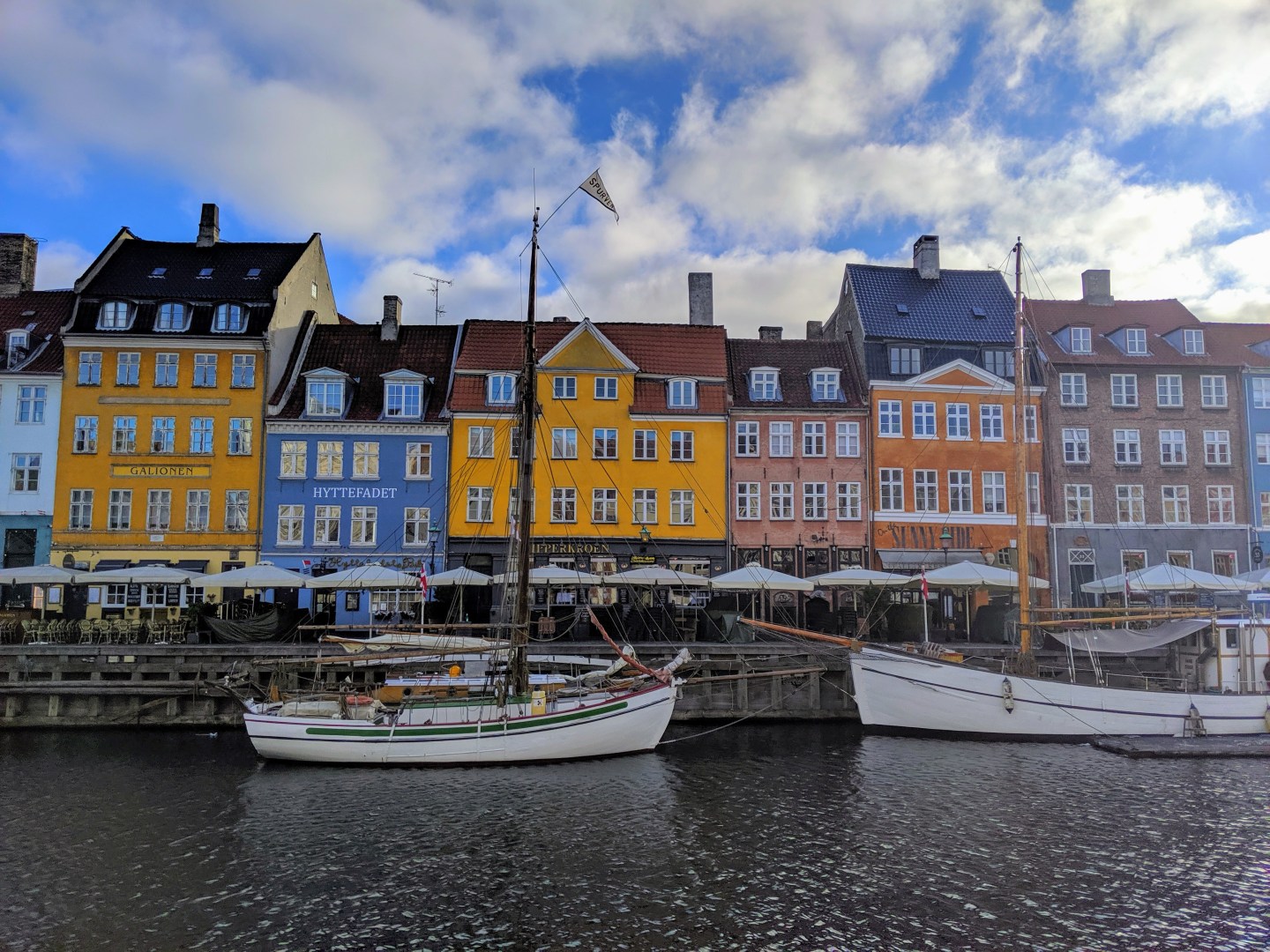 Nyhavn, the 17th century waterfront with row of colourful historic buildings, promenade and moored sailing ships in Copenhagen, Denmark.