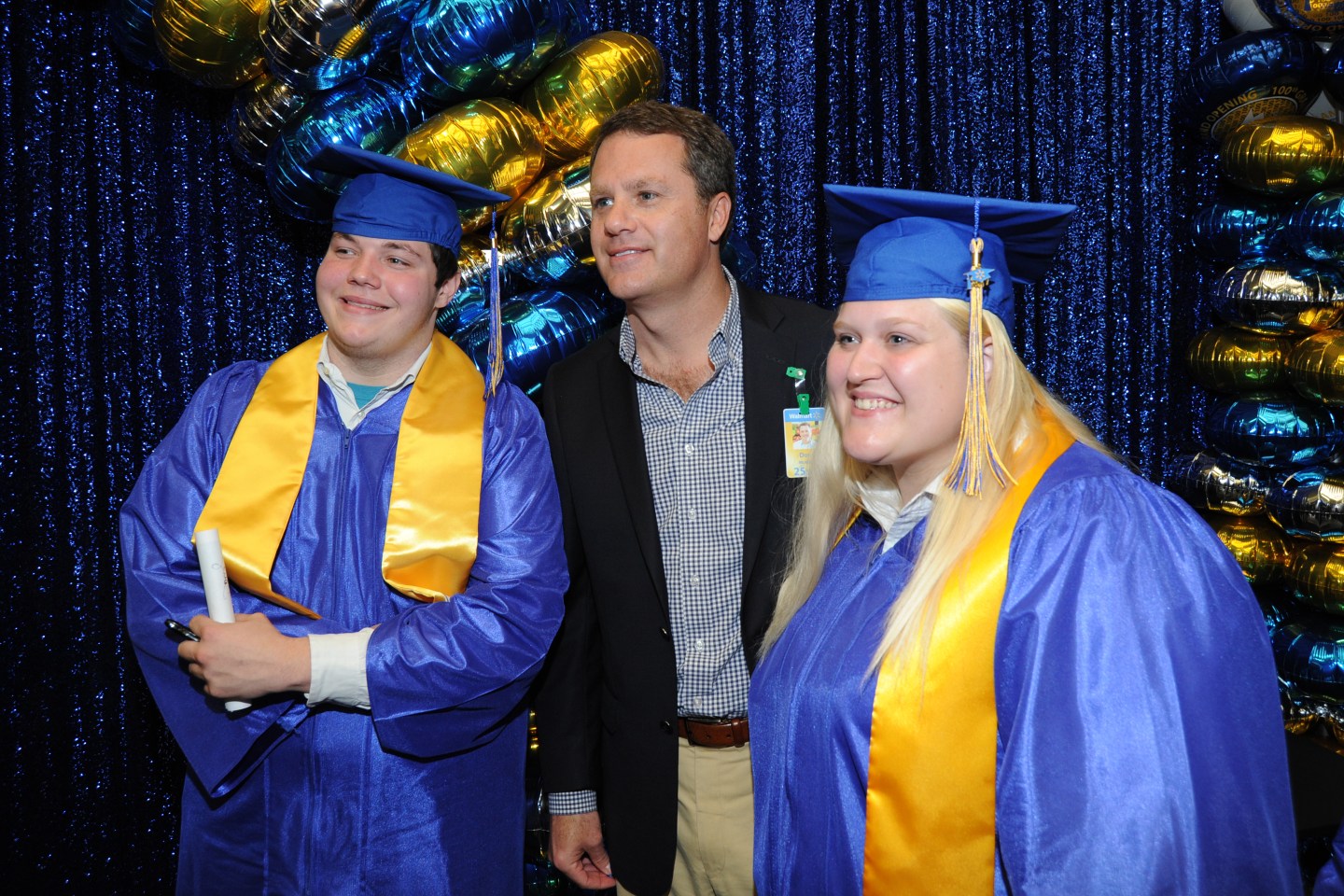 Walmart CEO Doug McMillon poses with two Academy graduates graduates.