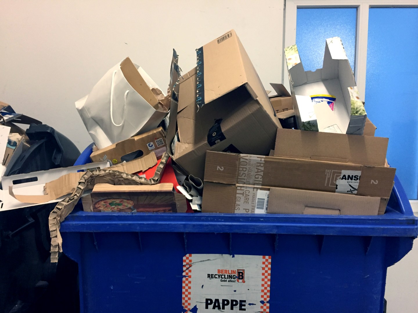 Berlin: Waste paper barrels full to bursting with paper, cardboard and cardboard are placed in a garbage room.