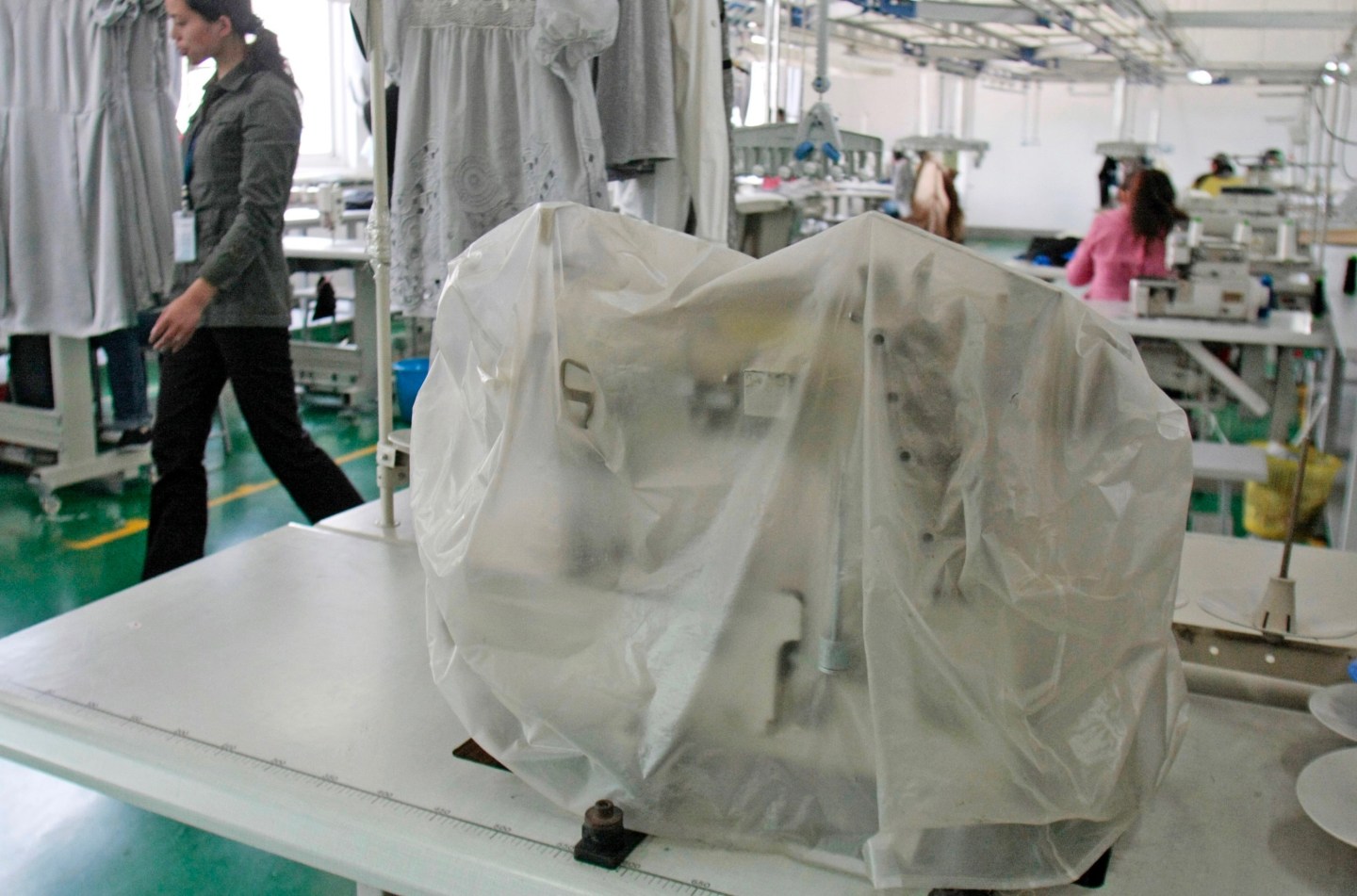 A woman walks past a sewing machine at the Ever-Glory Intern