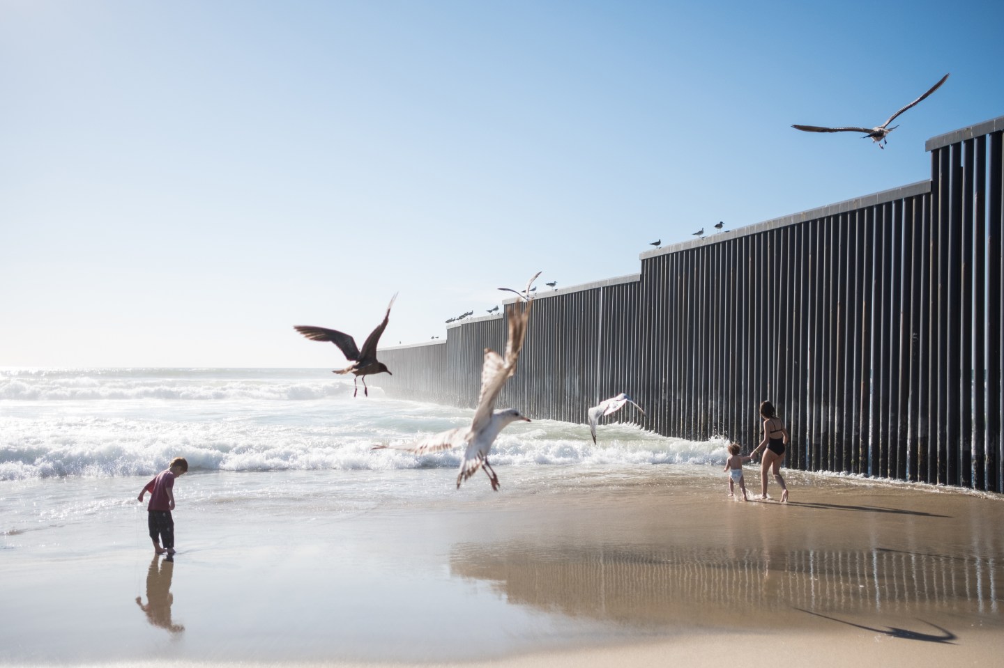 Kids are seen playing near the dividing border wall between