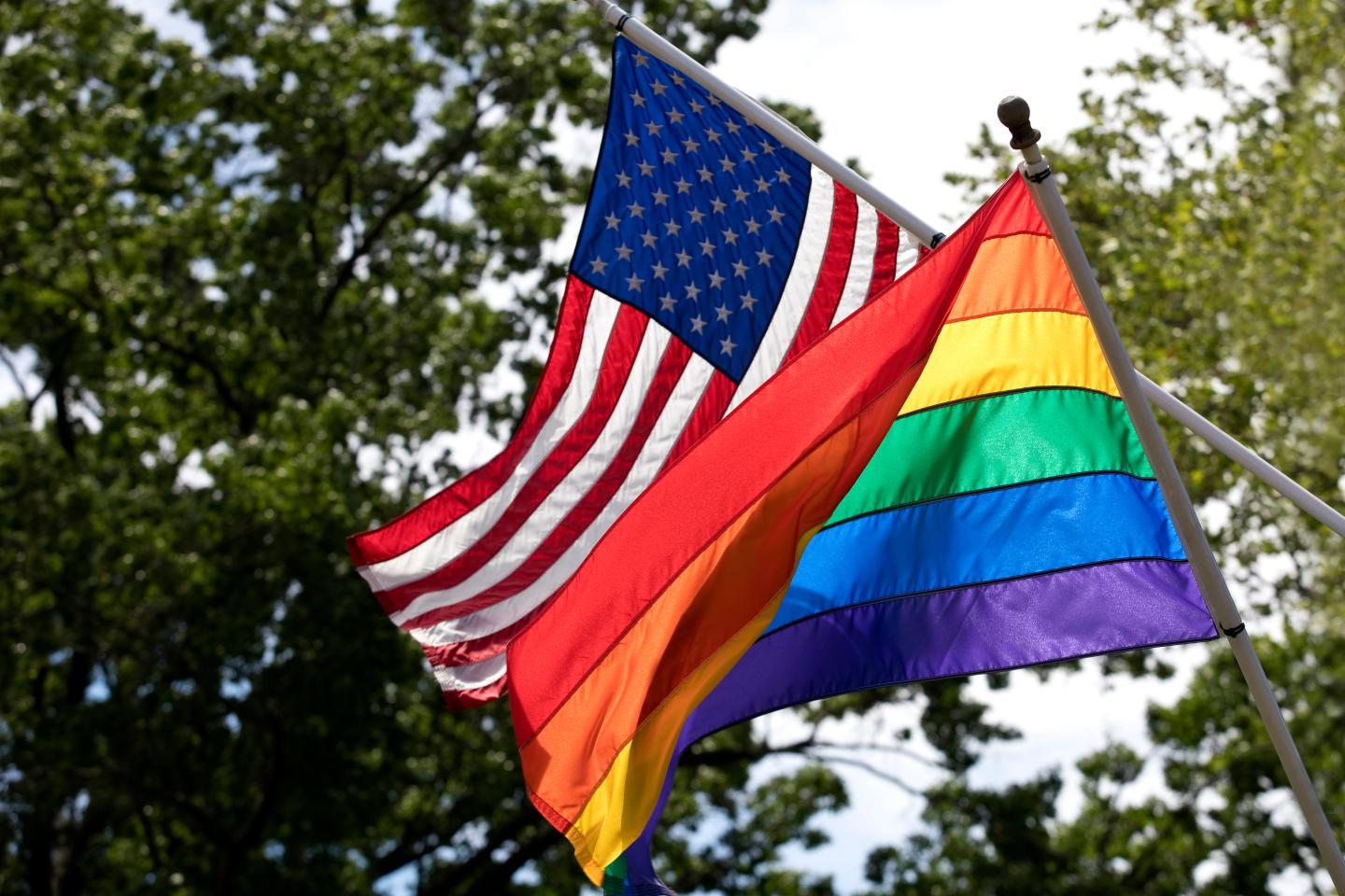 The rainbow pride and American flags fly in the wind together.