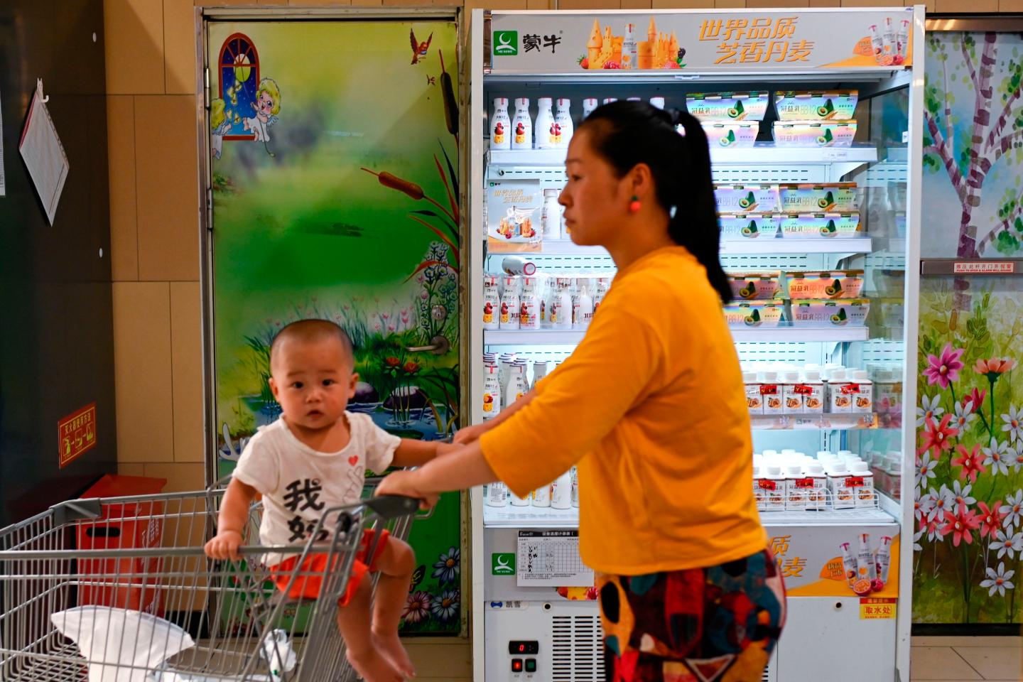 A customer and child are seen past a refrigerator displaying Mengniu milk products at a store in Beijing on June 24, 2019. - Coca-Cola and Chinese dairy firm Mengniu have signed a deal to become joint sponsors of the Olympic Games from 2021 to 2032, IOC chief Thomas Bach announced on June 24. (Photo by WANG Zhao / AFP) (Photo credit should read WANG ZHAO/AFP/Getty Images)