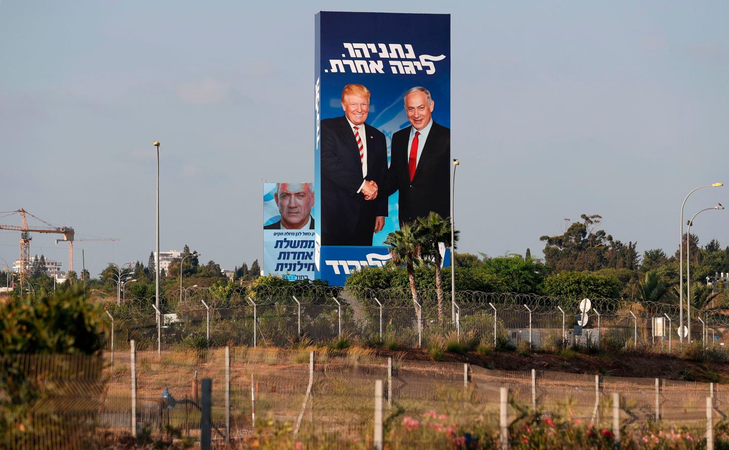 This picture taken on September 9, 2019 shows Israeli election billboards in the Israeli coastal city of Tel Aviv (R to L) for the Likud party showing US President Donald Trump shaking hands with Likud chairman and Prime Minister Benjamin Netanyahu with a caption in Hebrew reading "Netanyahu, in another league"; and another for the "Blue and White" (Kahol Lavan) electoral alliance showing the face of retired general Benny Gantz and a caption in Hebrew reading "only with the Blue and White will create a united secular government".