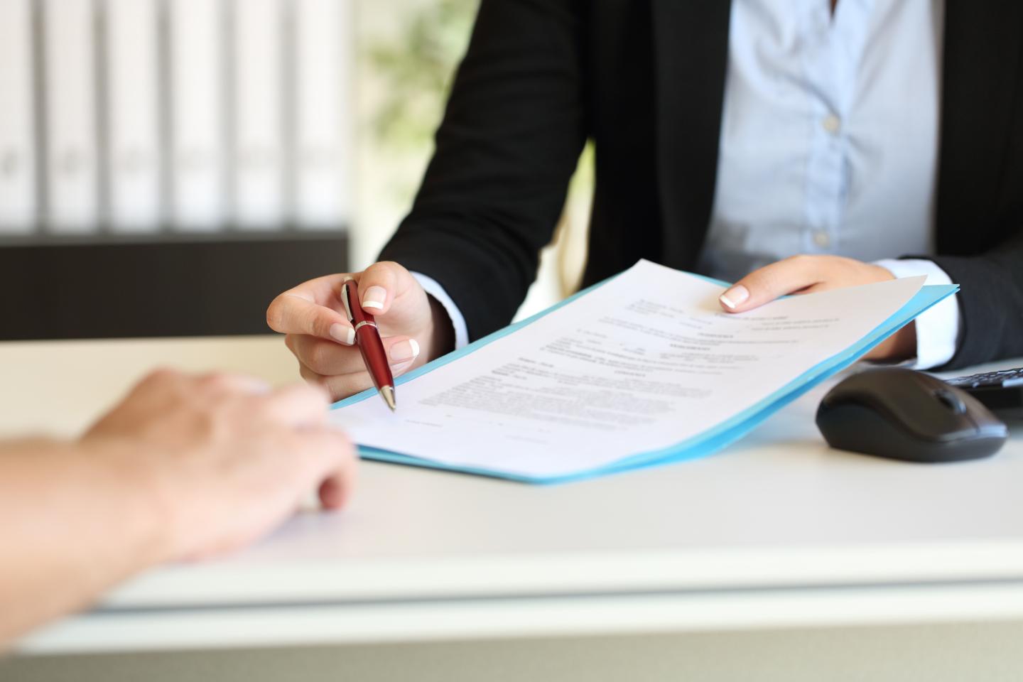 Photo of man handing a contract to another person to sign.