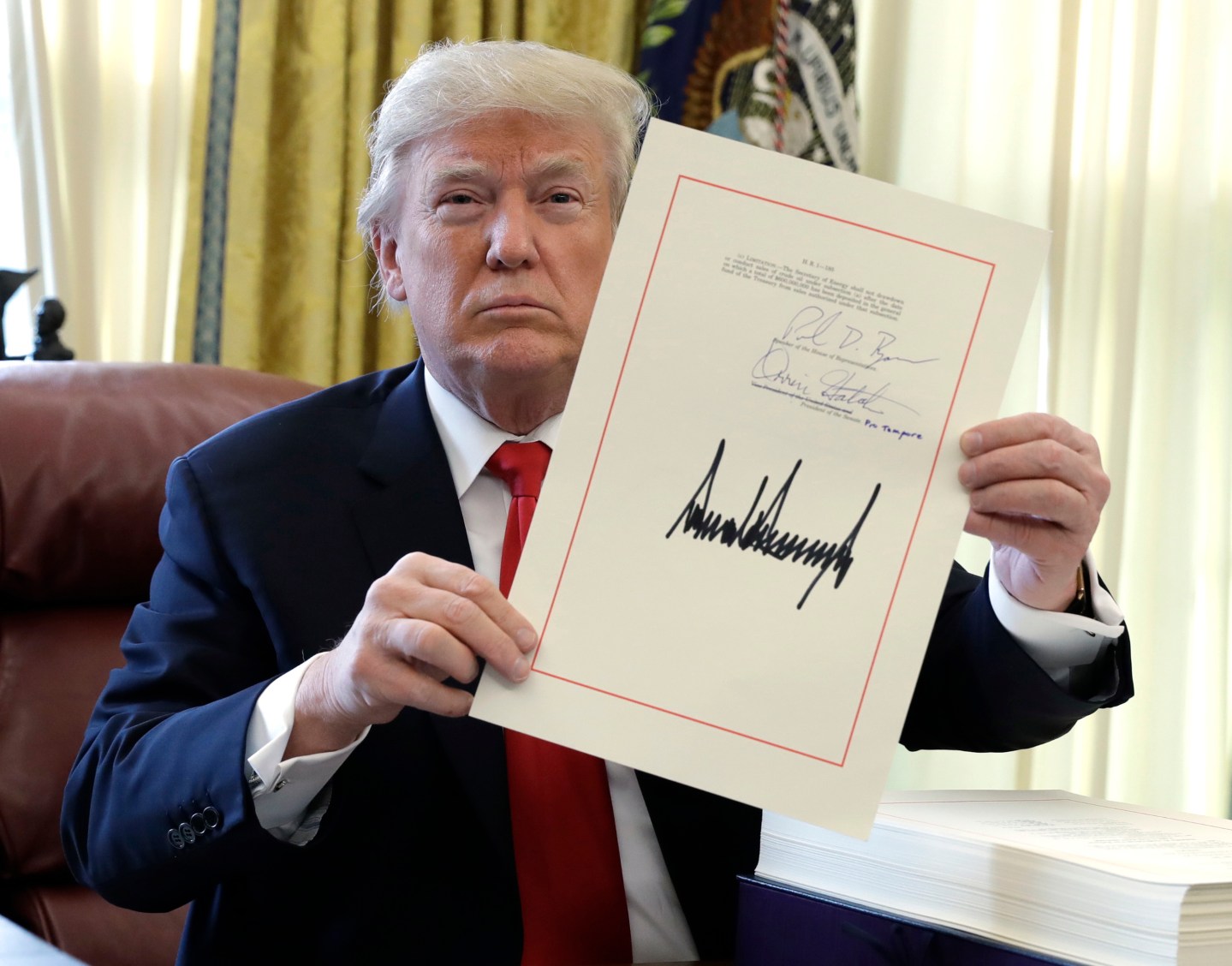 Donal Trump holding his signed tax reform bill