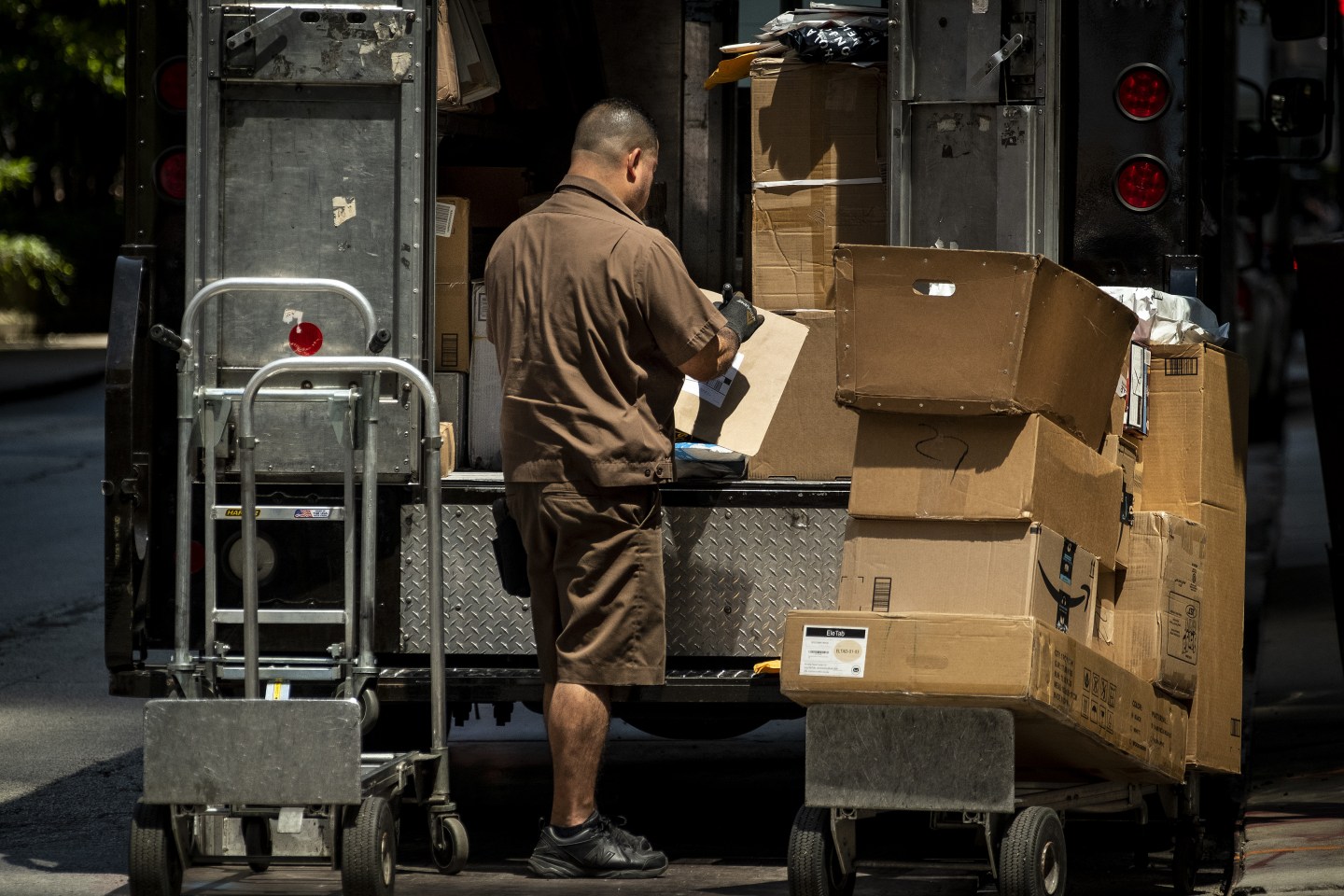 A driver for an independent contractor to United Parcel Service Inc. (UPS) places packages on a dolly to be delivered in Chicago, Illinois, U.S., on Monday, July 22, 2019. UPS is scheduled to release earnings figures on July 24. Photographer: Christopher Dilts/Bloomberg via Getty Images