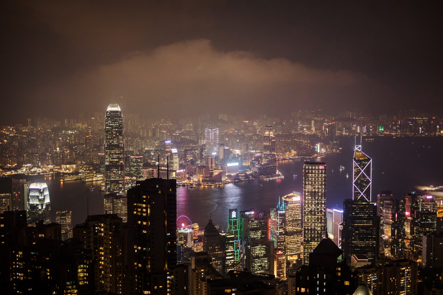 The Hong Kong skyline is shown at night in a layer of cloudy fog.
