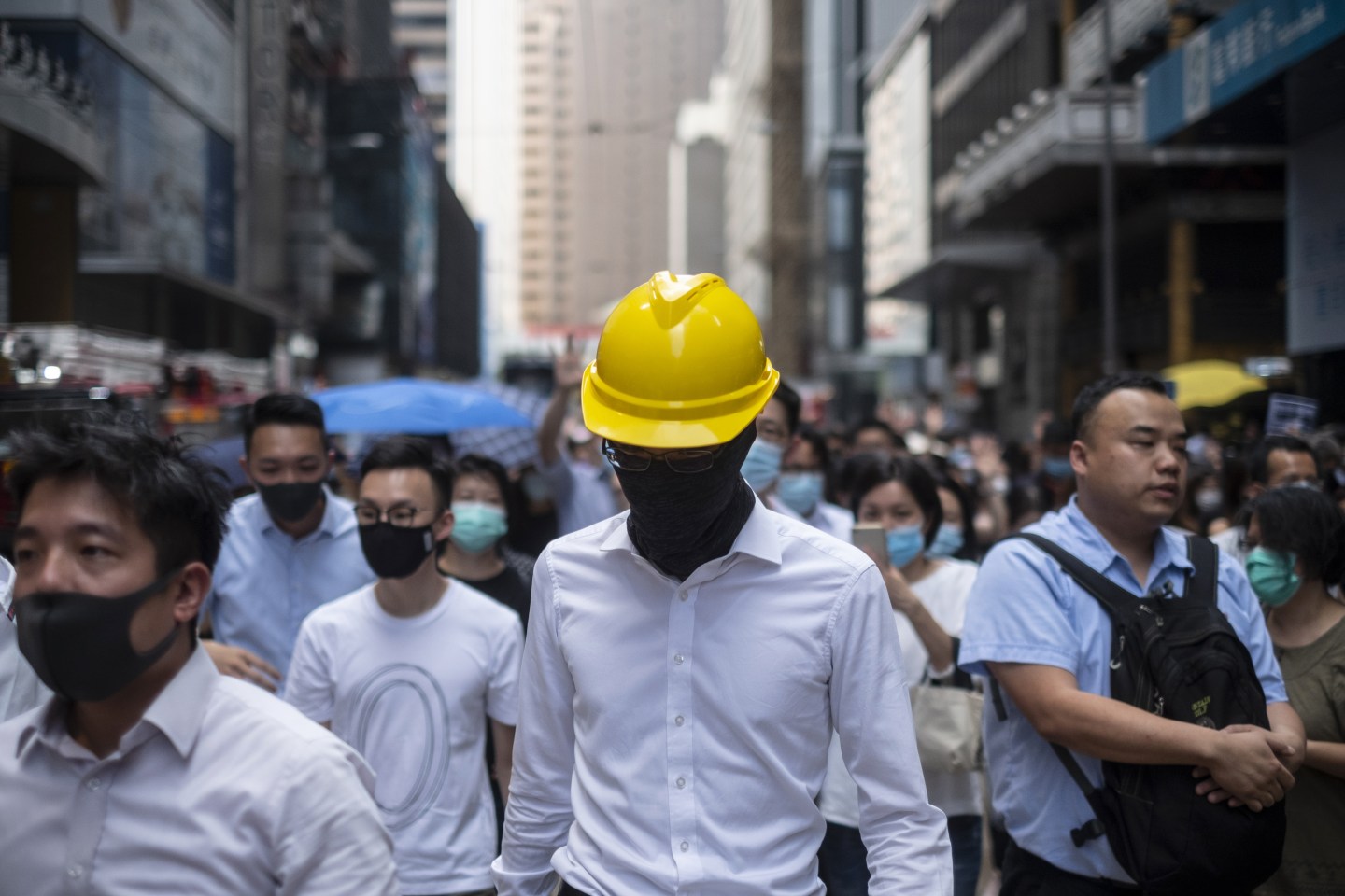 A demonstrator wearing a hard hat marches along Des Voeux Road Central during a flash mob in the Central district of Hong Kong, China, on Friday, Oct. 4, 2019. Hong Kong invoked emergency rule for the first time in a half a century to ban face masks on protesters, Now TV reported, as authorities look to quell months of unrest. Photographer: Chan Long Hei/Bloomberg via Getty Images