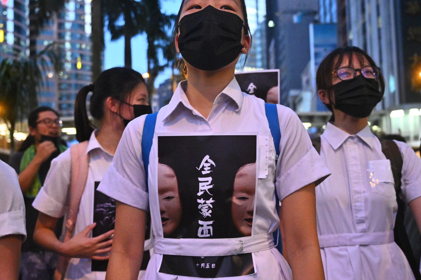 High school students chant slogans as they stick posters reading "all people masked" on their uniforms as protesters gather in the heart of Hong Kong's commercial district Central on October 4, 2019, after the government announced a ban on facemasks. - Hong Kong's leader invoked colonial-era emergency powers on October 4 to ban protesters wearing face masks, but the move aimed at quelling months of unrest sparked immediate fresh rallies and vows to defy the new law. (Photo by Philip FONG / AFP) (Photo by PHILIP FONG/AFP via Getty Images)