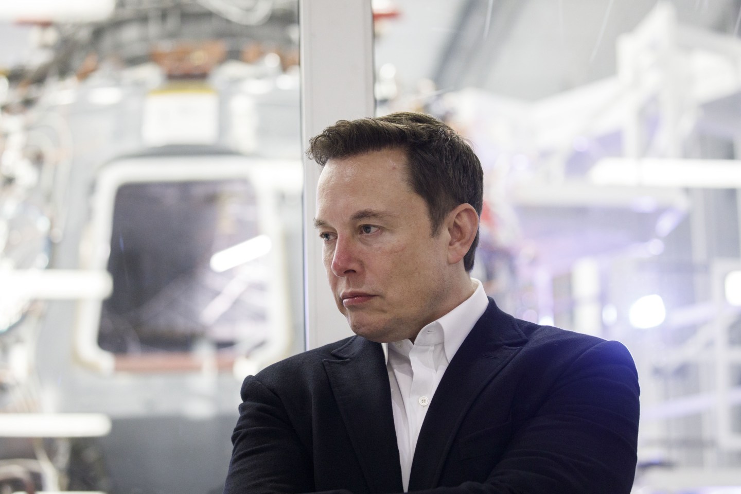 Elon Musk at SpaceX headquarters looking off to the side with a blank stare