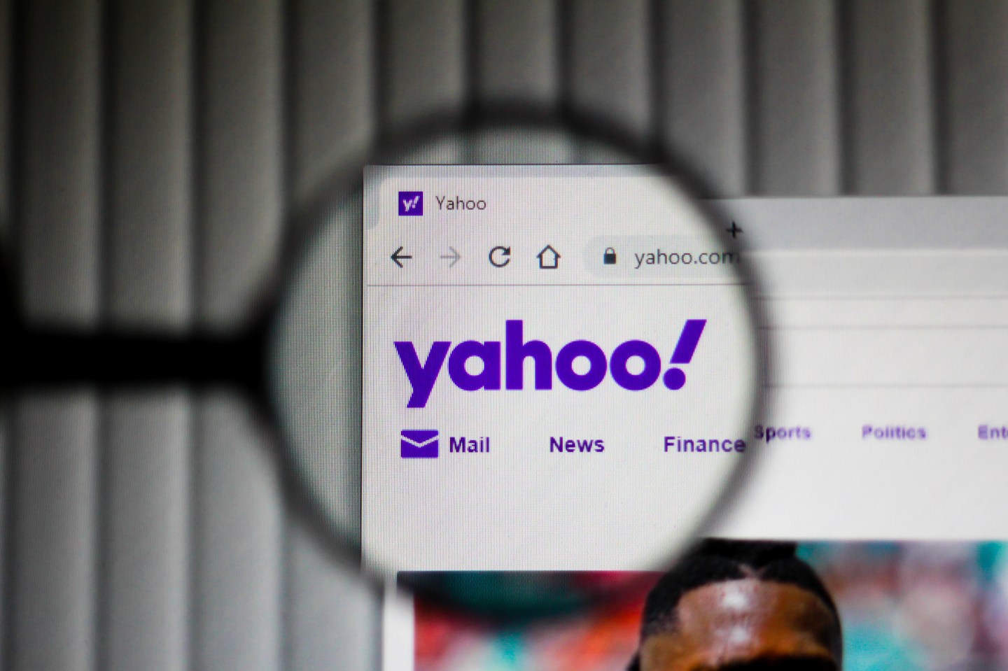 The Yahoo homepage appears blurred except for one portion that is clearly visible through the lens of a magnifying glass, which shows the Yahoo logo.
