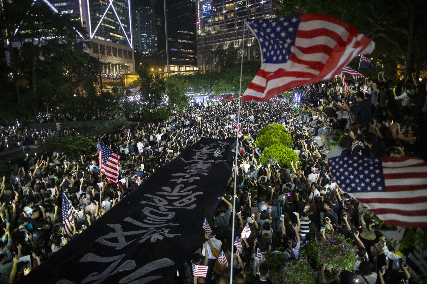 Demonstrations hold a banner and American flags during a rally in support of the Hong Kong Human Rights and Democracy Act in Hong Kong, China, on Monday, Oct. 14, 2019. Protesters gathered in the city's central district in a police-sanctioned rally in support of the Hong Kong Human Rights and Democracy Act, a bill proposed in the U.S. to impose sanctions on the city. Photographer: Chan Long Hei/Bloomberg via Getty Images