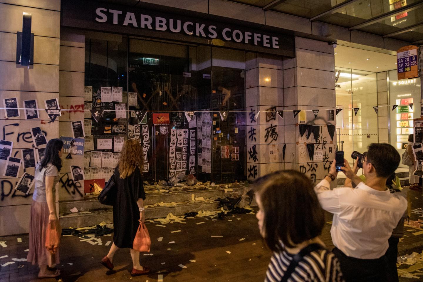 HONG KONG, CHINA - OCTOBER 01: People take photographs of a Starbucks shop damaged by pro-democracy protesters during clashes with police on October 01, 2019 in Hong Kong, China. Pro-democracy protesters marked the 70th anniversary of the founding of the People's Republic of China in Hong Kong through demonstrations as the city remains on the edge with the anti-government movement entering its fourth month. Protesters in Hong Kong continue its call for Chief Executive Carrie Lam to meet their remaining demands since the controversial extradition bill has been withdrawn, which includes an independent inquiry into police brutality, the retraction of the word “riot” to describe the rallies, and genuine universal suffrage, as the territory faces a leadership crisis. (Photo by Chris McGrath/Getty Images)