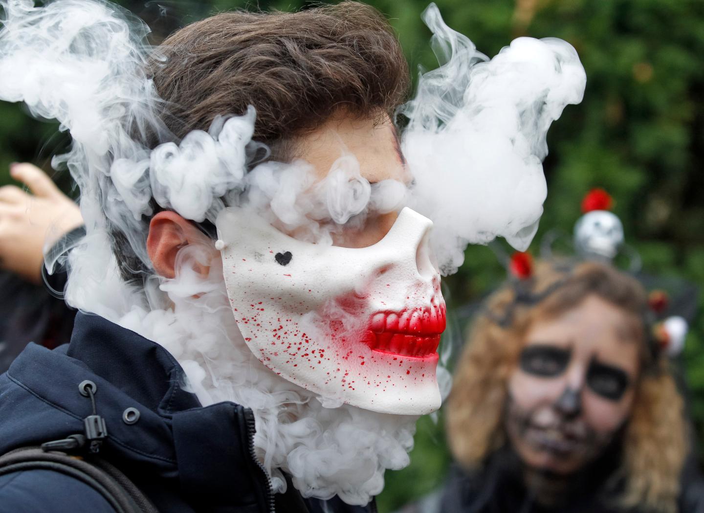 KIEV, UKRAINE - 2019/10/26: A participant wearing a mask smoking electronic cigarette attend the Halloween parade in Kiev. Hundreds of zombies staggered through the inner city in search of fresh brains during the Halloween Parade. Halloween is a holiday celebrated in the world on 31 October, the eve of the Western Christian feast of All Hallows' Day in which participants attend the Halloween costume parties, carving pumpkins into jack-o'-lanterns, lighting bonfires, apple bobbing, playing pranks, tell scary stories and watch horror films. (Photo by Pavlo Gonchar/SOPA Images/LightRocket via Getty Images)