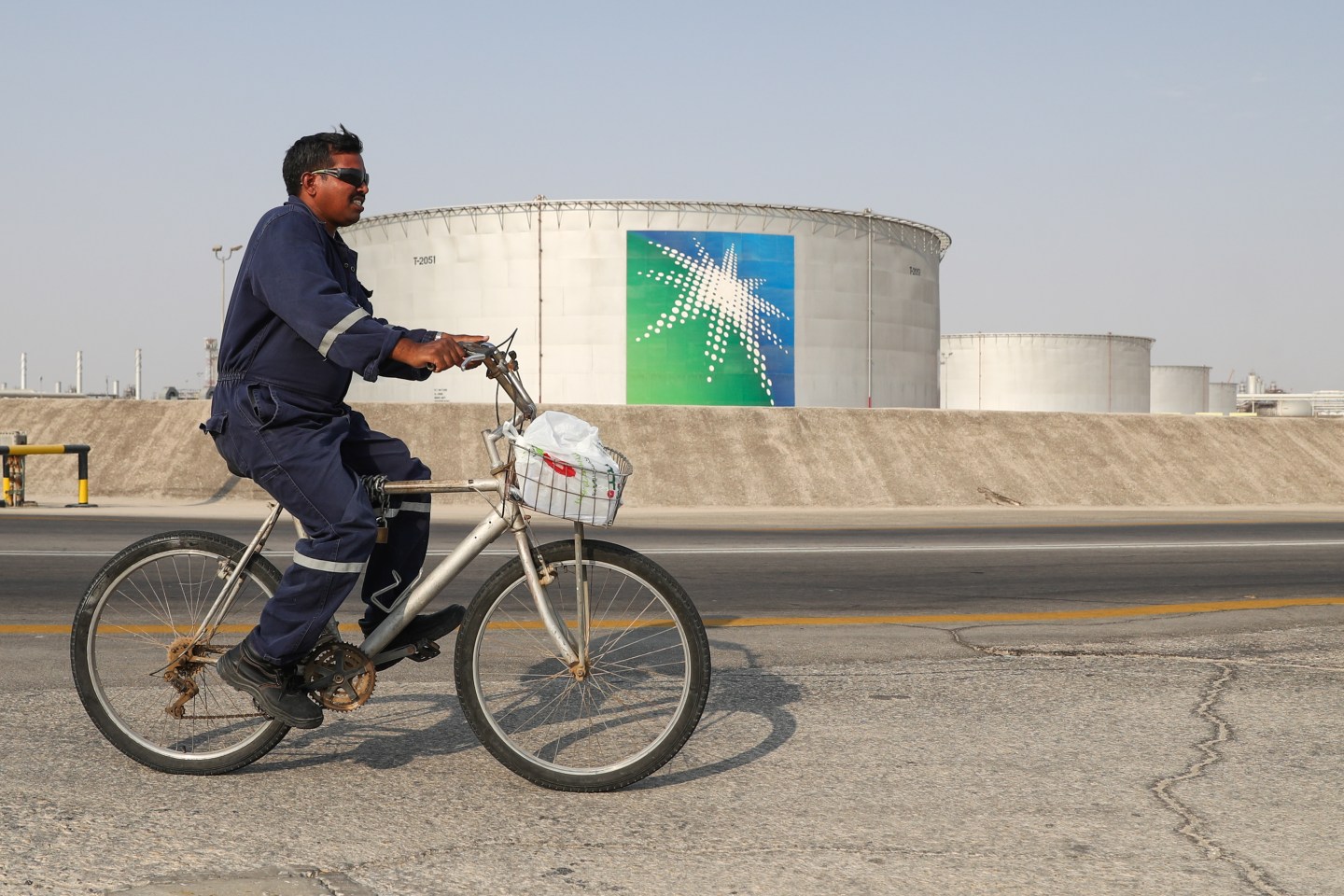 EASTERN PROVINCE, SAUDI ARABIA - OCTOBER 12, 2019: A worker rides a bicycle by oil tanks at an oil processing facility of Saudi Aramco, a Saudi Arabian state-owned oil and gas company, at the Abqaiq oil field. On 14 September 2019, two of the major Saudi oil facilities, Abqaiq and Khurais, suffered massive attacks of explosive-laden drones and cruise missiles; the Houthi movement, also known as Ansar Allah, claimed responsibility for the attacks. Stanislav Krasilnikov/TASS (Photo by Stanislav KrasilnikovTASS via Getty Images)