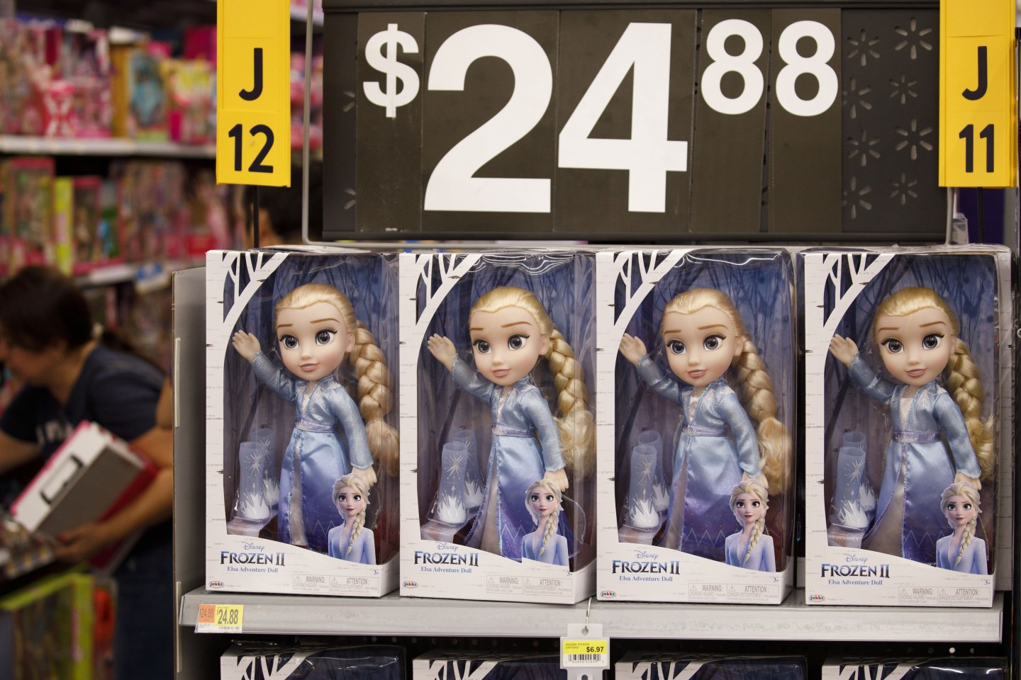Four "Frozen II" Elsa dolls are lined up in boxes on a store shelf under a sign marking them $24.88.