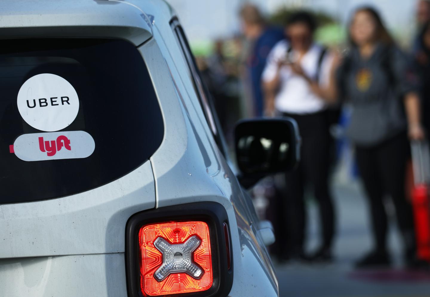 Arriving passengers wait to board Uber vehicles at the new 'LAX-it' ride-hail passenger pickup lot at Los Angeles International Airport (LAX) on Nov. 6, 2019 in Los Angeles, California. The airport has instituted a ban on Lyft, Uber and taxi curbside pickups as airport construction increases during a modernization program. Passengers have complained of long wait times and confusion at the pickup area, especially during peak hours. Passengers must depart their terminal and then ride a shuttle bus or walk to the separate pickup lot. (Photo by Mario Tama/Getty Images)