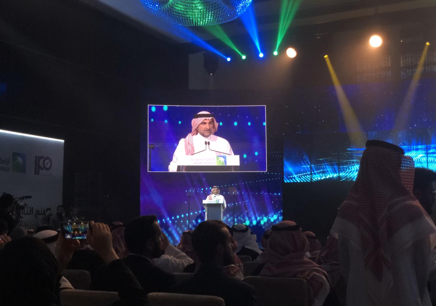(EDITORS NOTE: Best quality available, image shot using a smartphone.) Yasir Al-Rumayyan, chairman of Saudi Aramco, speaks to participants during the ceremony to mark the initial public offering (IPO) of Saudi Aramco at the Fairmont Hotel in Riyadh, Saudi Arabia, on Wednesday, Dec. 11, 2019. Saudi Aramco shares surged after its initial public offering, valuing the oil producer at a record $1.88 trillion and lifting Saudi Arabias stock market into the ranks of the worlds largest. Photographer: Matthew Martin/Bloomberg via Getty Images