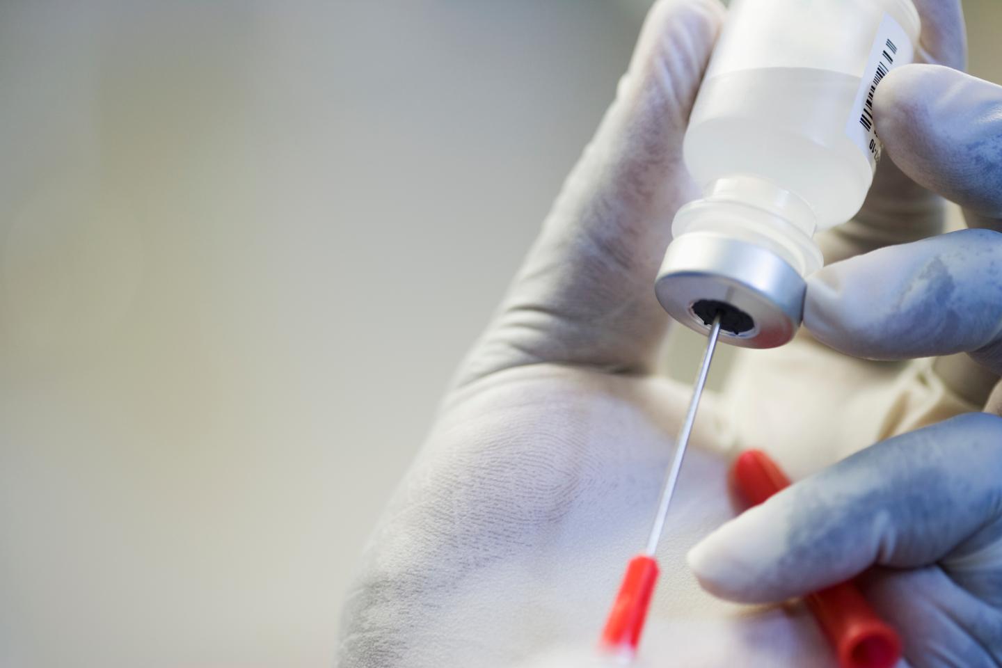 Close up of hand in rubber glove filling syringe