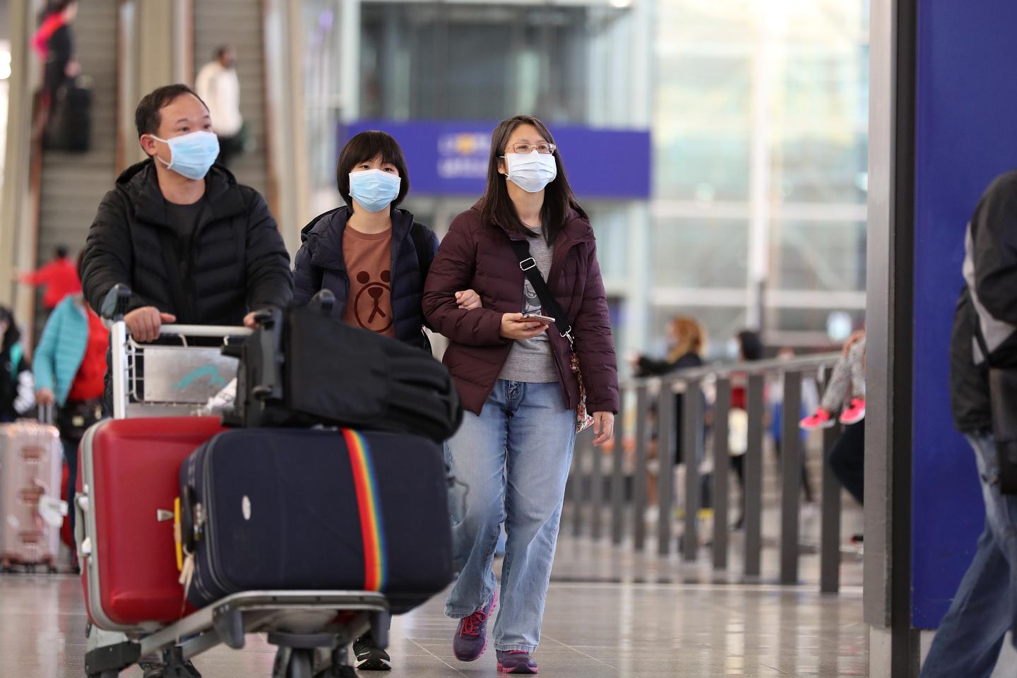 Travelers wearing face masks walk through the arrival hall at the Hong Kong International Airport in Hong Kong, China, on Wednesday, Jan. 22, 2020. China ramped up efforts to contain a new respiratory virus that's killed nine people and infected hundreds, as the outbreak spread to Asia's financial capital with the first reported case of the deadly illness in Hong Kong. Photographer: May James/Bloomberg via Getty Images