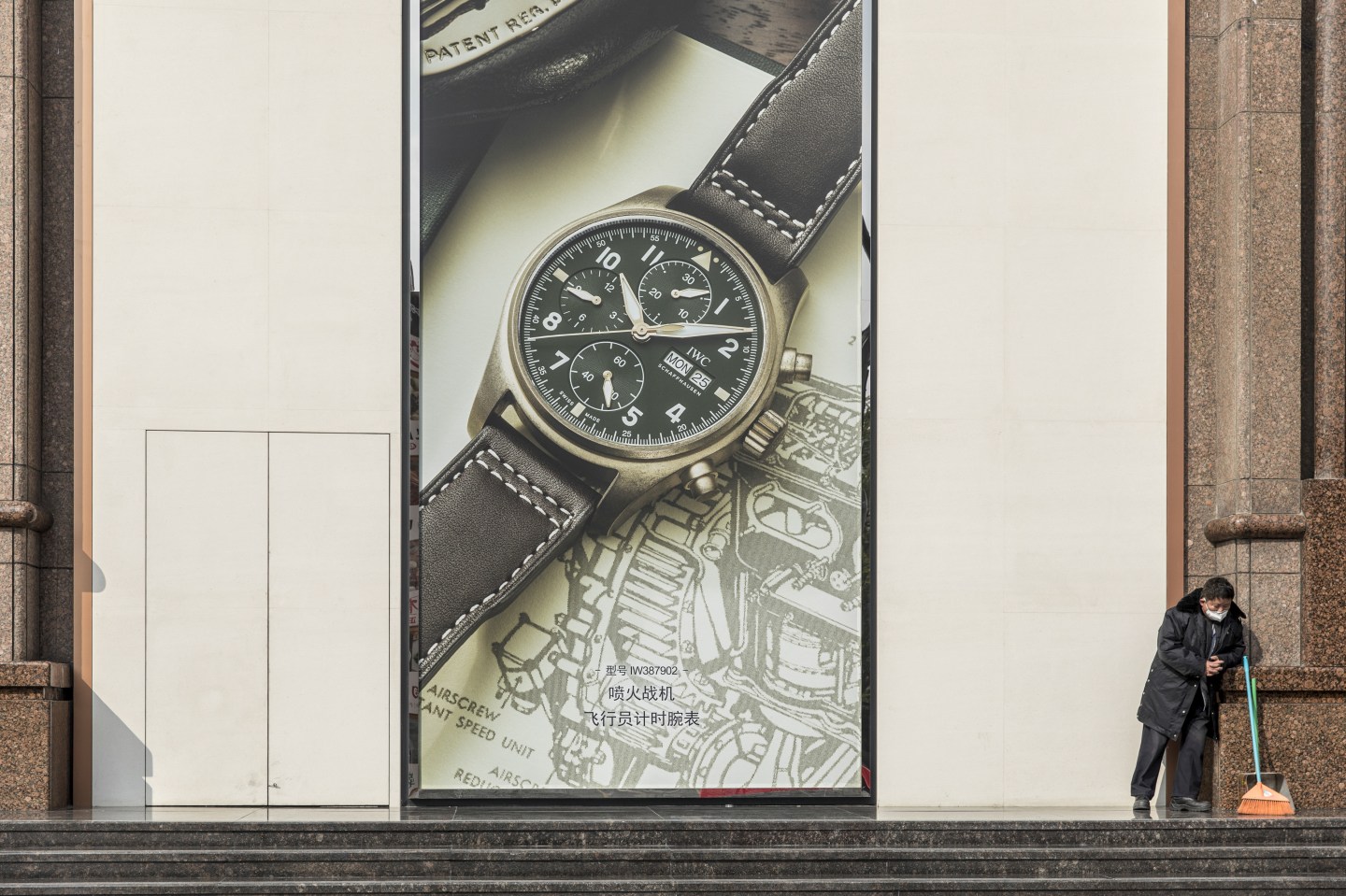 A worker stands next to a large advert for an IWC watch on an almost empty Nanjing Road, usually a busy commercial street, in Shanghai, China, on Wednesday, Jan. 29, 2020. The novel coronavirus spread further, with the number of confirmed cases in China soaring to overtake the official number of infections in the country during the SARS epidemic. Photographer: Qilai Shen/Bloomberg via Getty Images