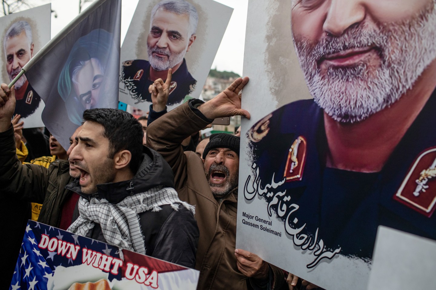 People hold posters showing the portrait of Iranian Revolutionary Guard Major General Qasem Soleimani