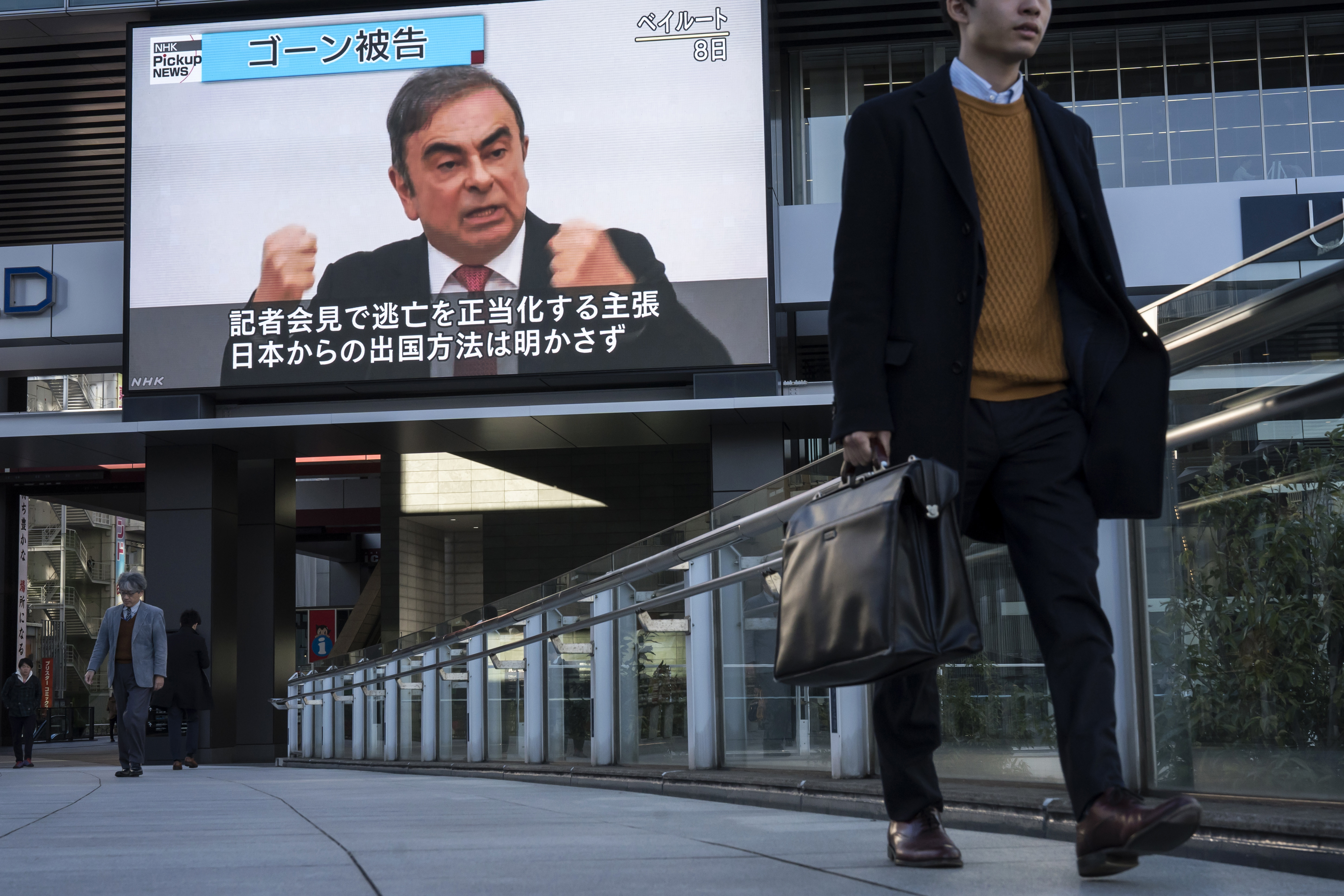 TOKYO, JAPAN - JANUARY 09: Pedestrians walk in front of a monitor displaying a news broadcast on former Nissan Motor Co. Chairman Carlos Ghosn on January 09, 2020 in Tokyo, Japan. Ghosn was awaiting trial in Japan on charges of financial crimes when he fled house arrest in Tokyo, arriving in Beirut on December 30. (Photo by Tomohiro Ohsumi/Getty Images)