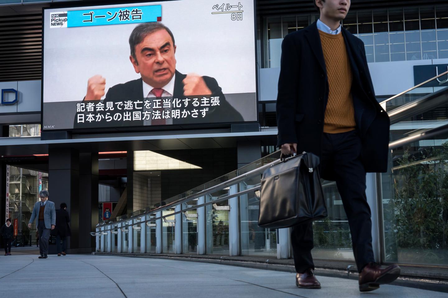 TOKYO, JAPAN - JANUARY 09: Pedestrians walk in front of a monitor displaying a news broadcast on former Nissan Motor Co. Chairman Carlos Ghosn on January 09, 2020 in Tokyo, Japan. Ghosn was awaiting trial in Japan on charges of financial crimes when he fled house arrest in Tokyo, arriving in Beirut on December 30. (Photo by Tomohiro Ohsumi/Getty Images)