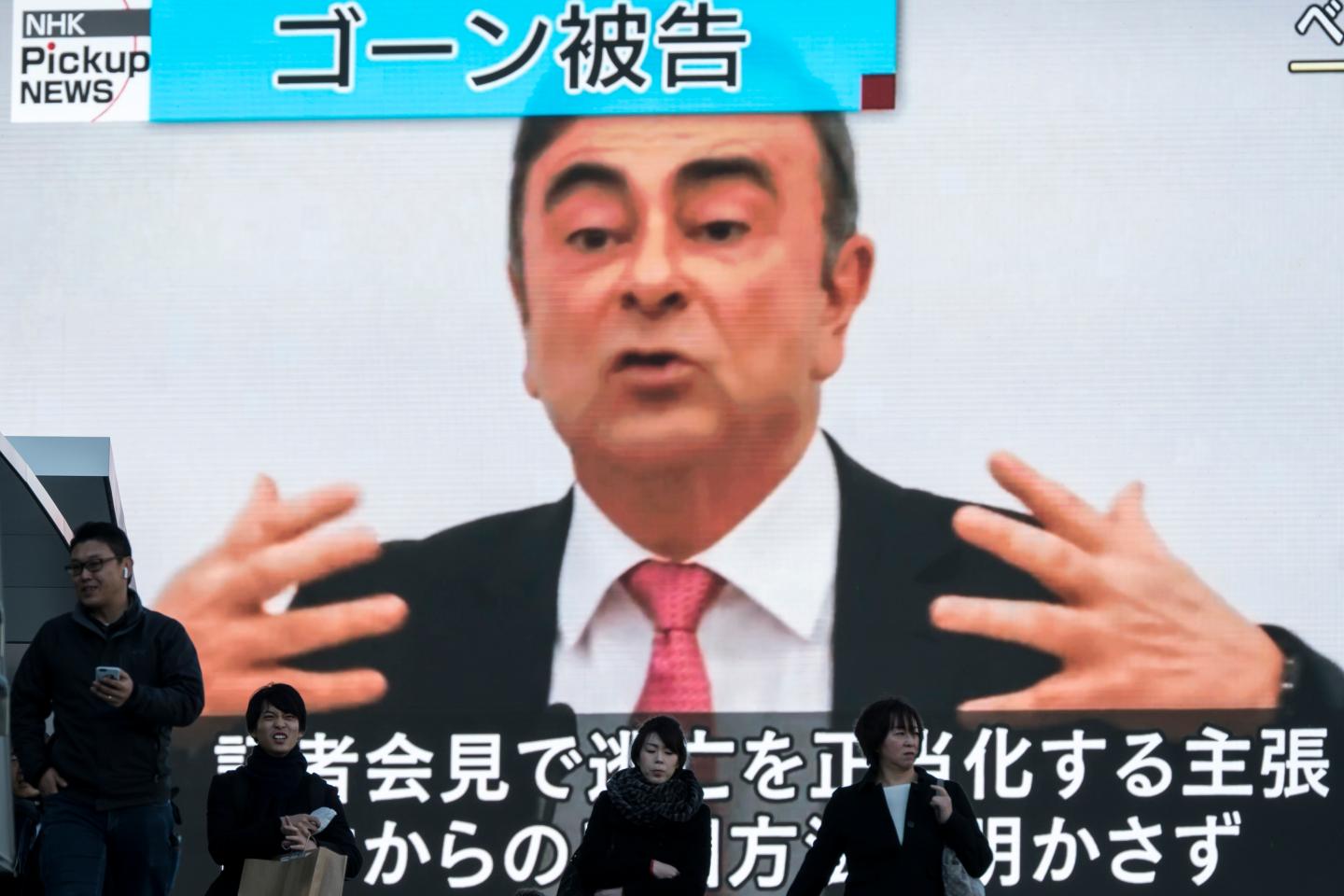 TOKYO, JAPAN - JANUARY 09: Pedestrians walk in front of a monitor displaying a news broadcast on former Nissan Motor Co. Chairman Carlos Ghosn on January 09, 2020 in Tokyo, Japan. Ghosn was awaiting trial in Japan on charges of financial crimes when he fled house arrest in Tokyo, arriving in Beirut on December 30. (Photo by Tomohiro Ohsumi/Getty Images)
