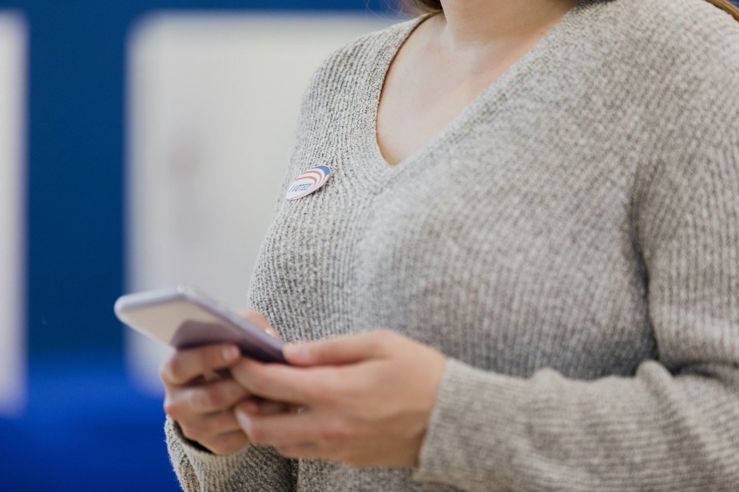 A woman wears her "I Voted" sticker as she looks at her smart phone. All eligible voters were able to cast their ballots via smartphone in a King County, Wash. election, Wednesday, the first time all eligible U.S. voters were allowed to vote online. iStock / Getty Images Plus