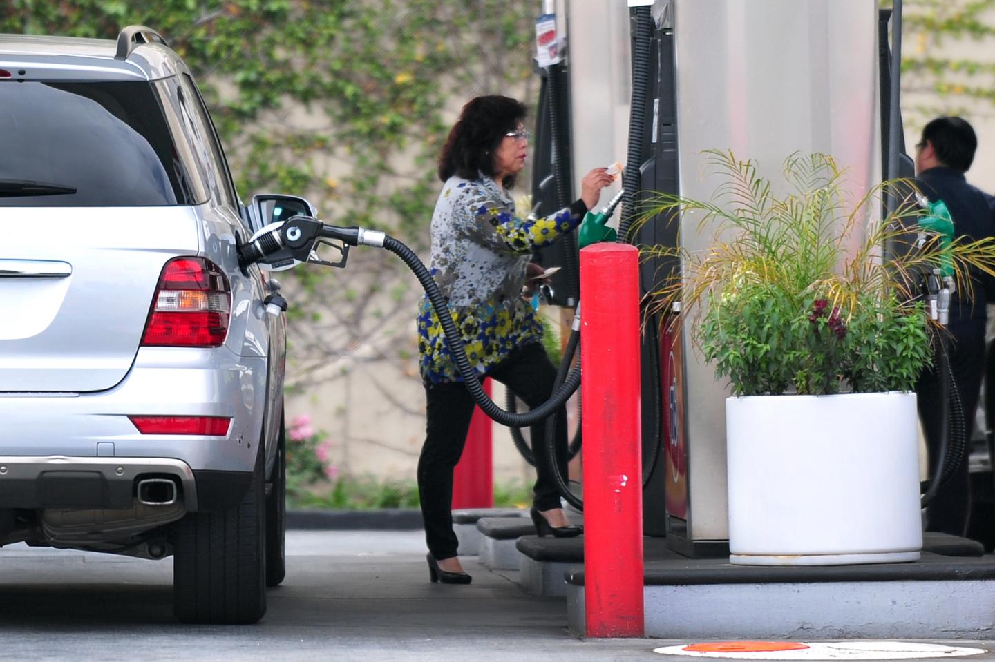 A driver pays for her gas while filling