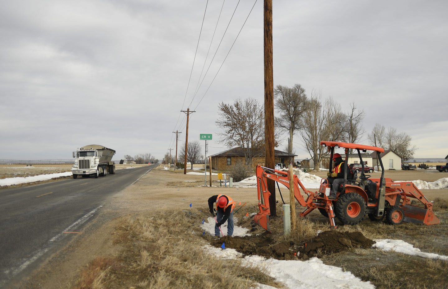 From left, Allen Scott and Seth Dawson, both with Blue Lightning, work on a hole to join fiber optic cable, for high speed internet, on December 19, 2019 in Wiggins, Colorado.