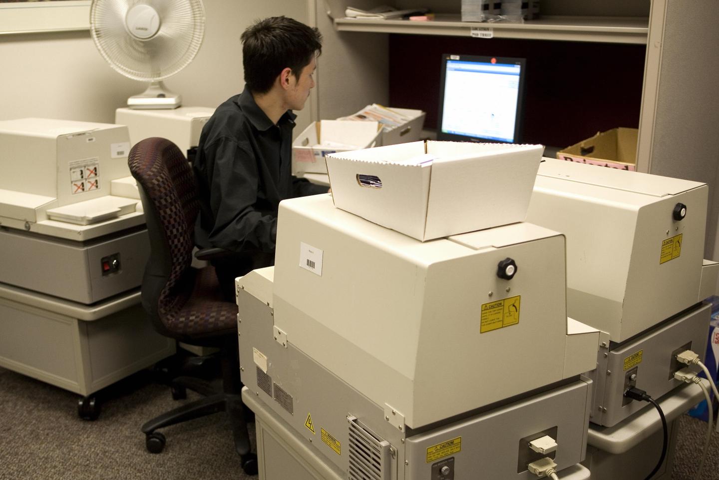 A US government official with the State Department's Passport Services works with four "book printers" for the processing of entering personal data and photographs of applicants 14 June 2007 at the Passport Services office in Washington, DC.